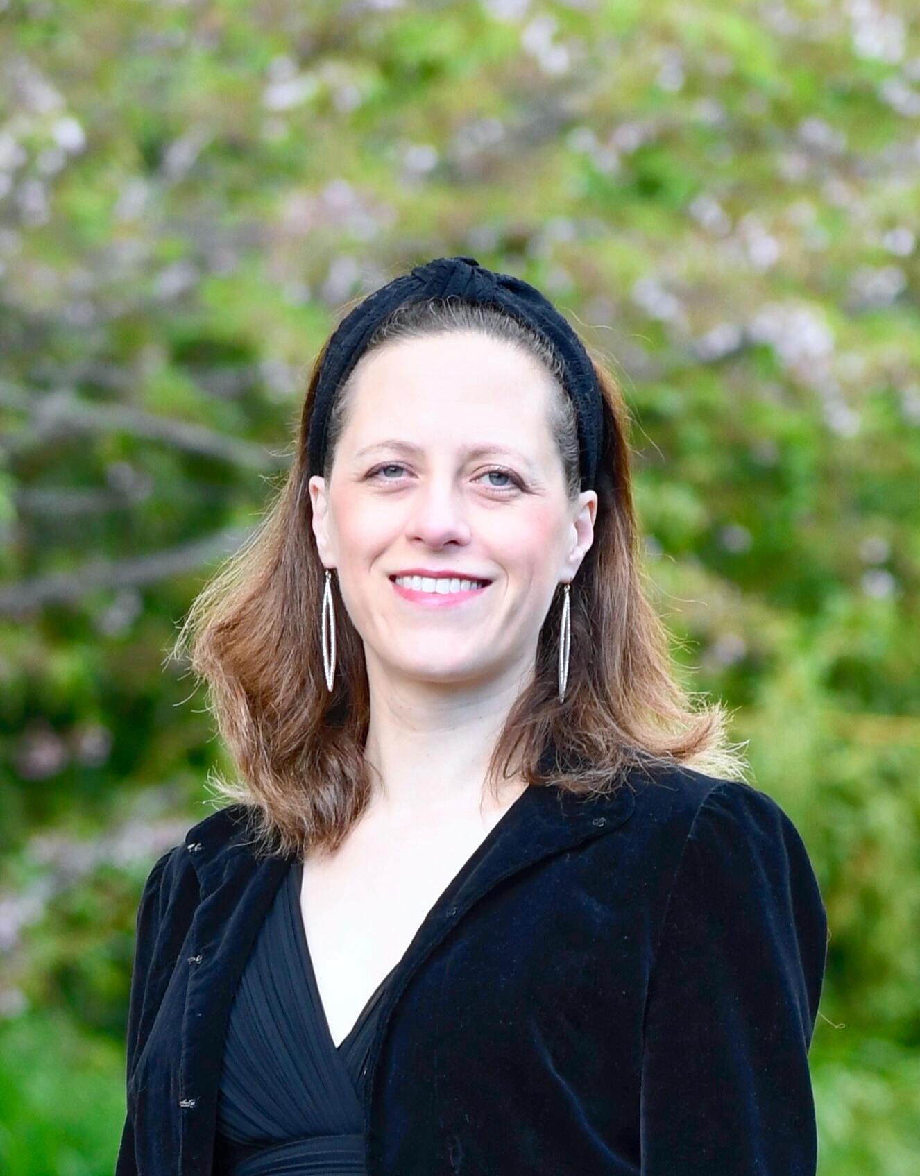 Rosemary Galton A portrait of Rosemary standing in front of some trees. She is wearing concert black clothes, and smiling,